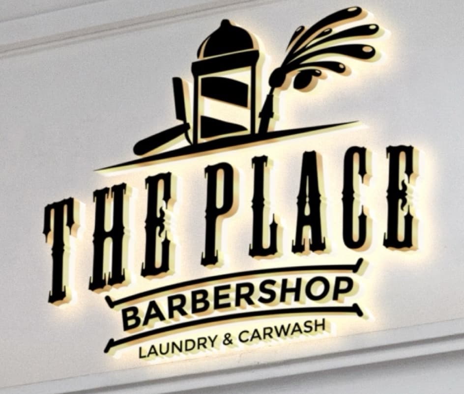 Close-up of the illuminated The Place Barbershop, Laundry & Carwash sign