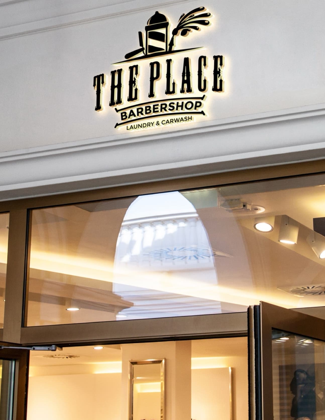 Illuminated “The Place Barbershop, Laundry & Carwash” sign above a shopfront